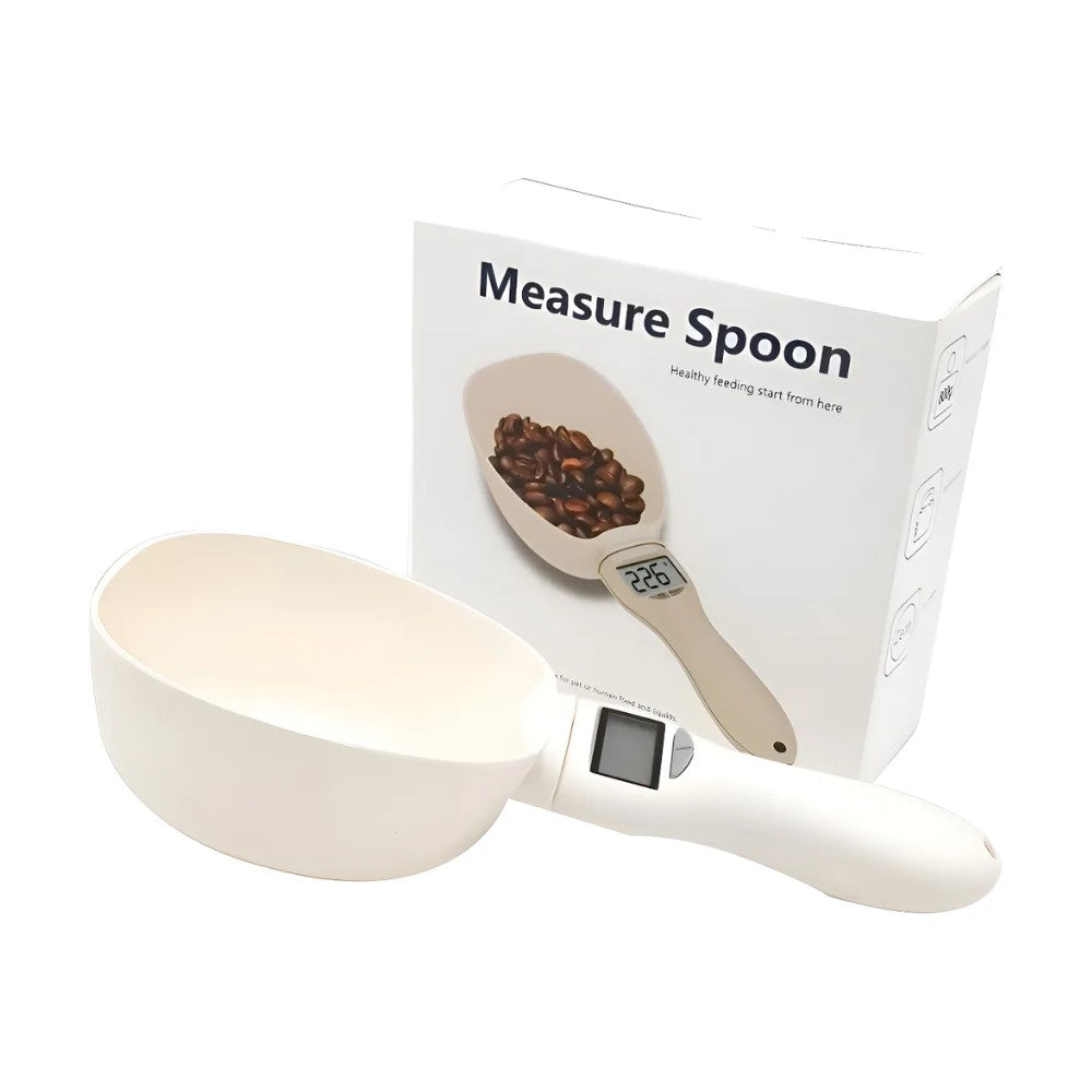 Balanza tipo cuchara blanca para medir porciones de croquetas, con pantalla digital en el mango y caja “Measure Spoon” al fondo
