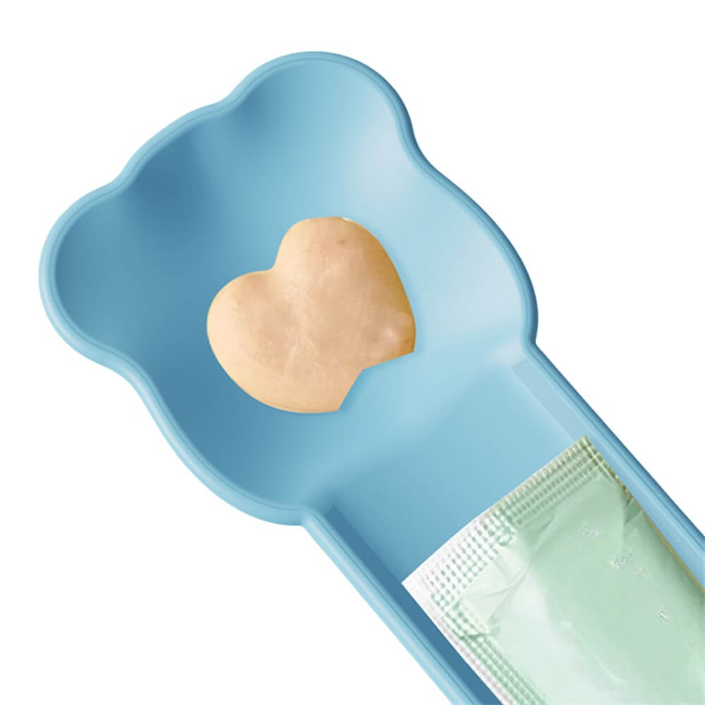 Parte superior de cuchara exprimidora azul para gatos, se aprecia un sachet de snack insertado y una porción de pasta crema en la cavidad