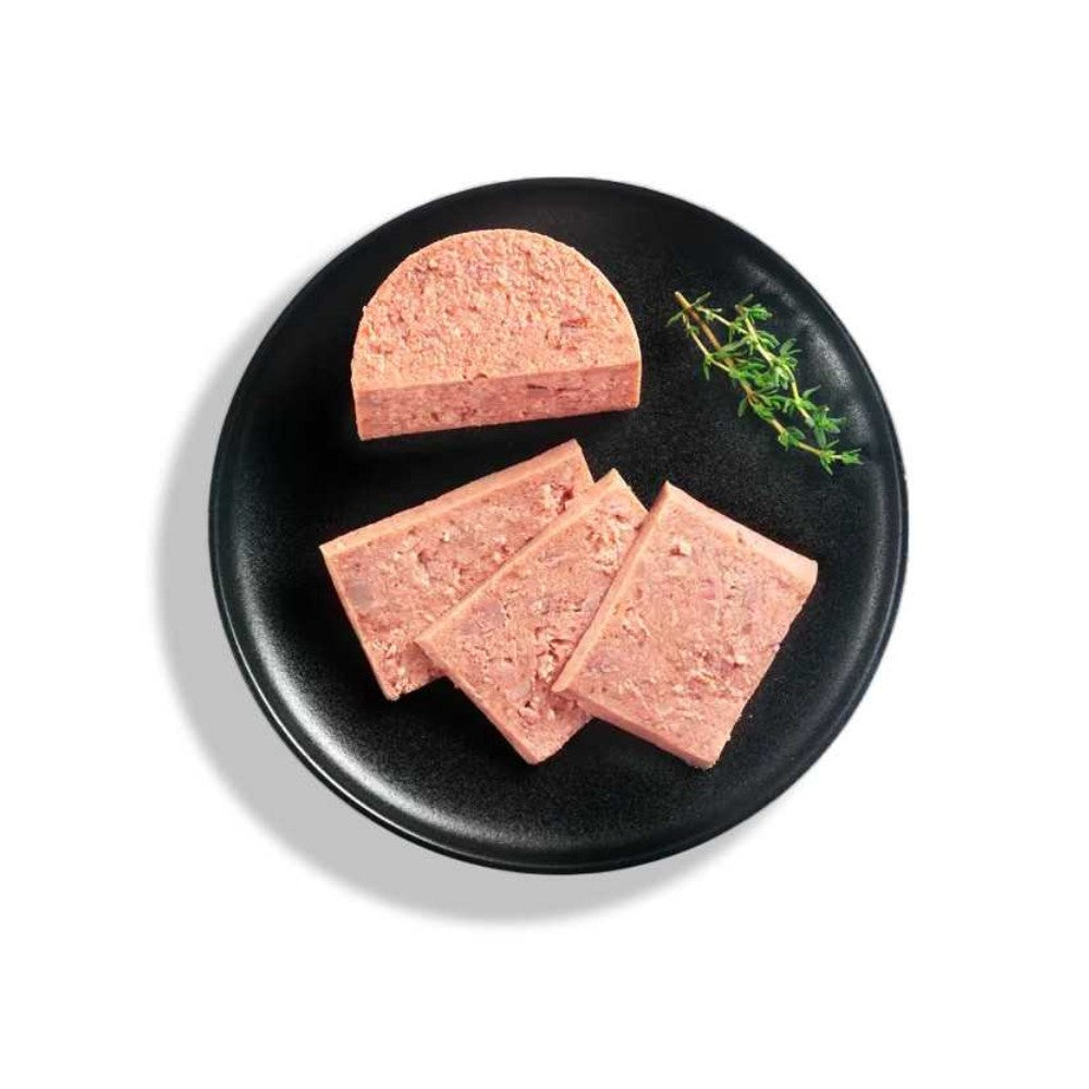 Plato negro con alimento húmedo Leonardo gatos tipo paté de pollo, cortado en rebanadas, acompañado de una ramita de tomillo